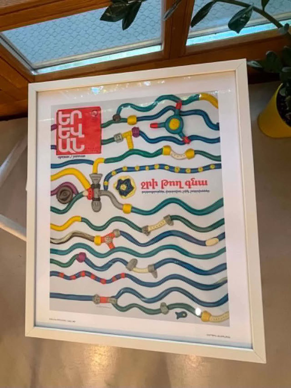 A framed Yerevan magazine cover with colourful plasticine-like pipes and tubes weaving across a white background