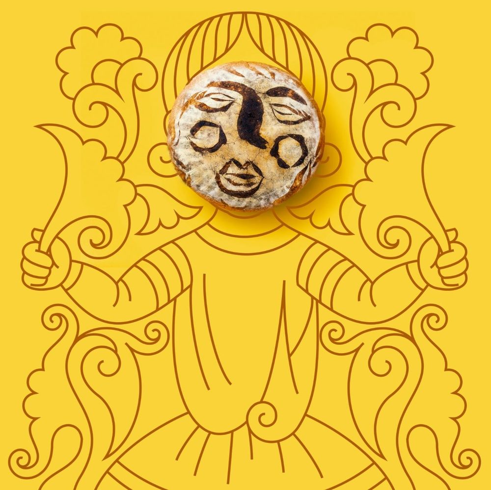 A sourdough loaf scored with a face, framed as the head of a drawn figure