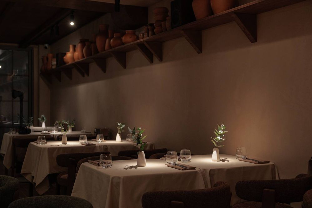 The warm, candlelit dining room of Puri, lined with clay jugs